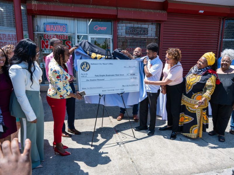 Baltimore Mayor Brandon Scott stands with other people around a large check.