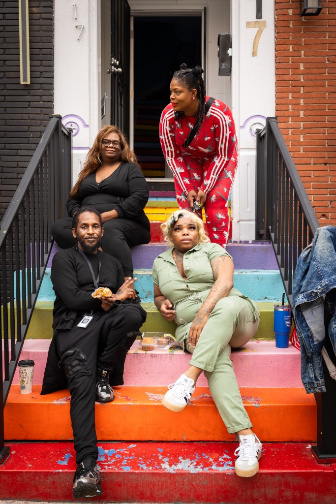 A group of people sit on colorful steps outside of a building.
