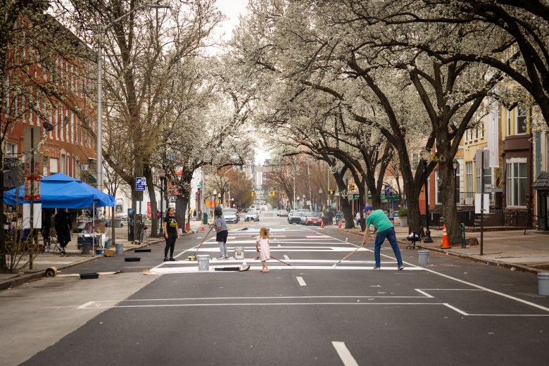 Adults and children work on the street painting.