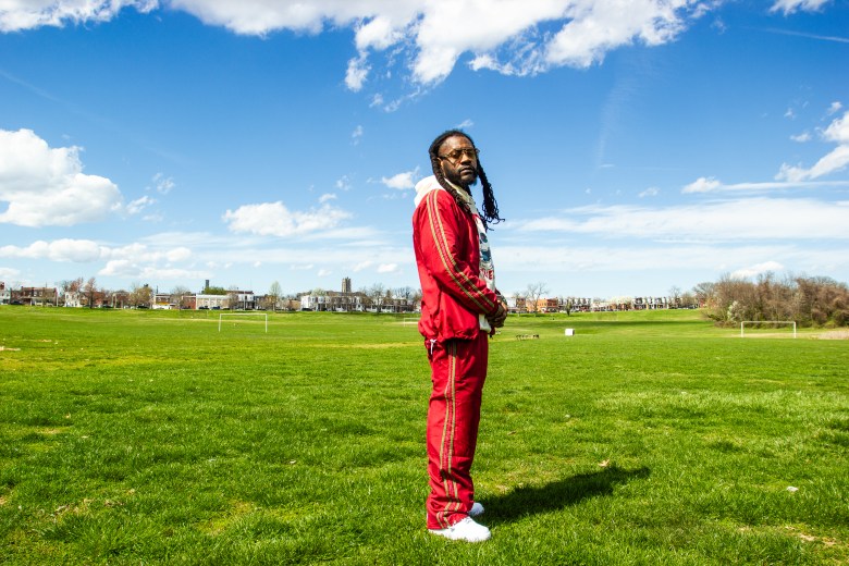 Photo of a man with brown skin posing in a green field 