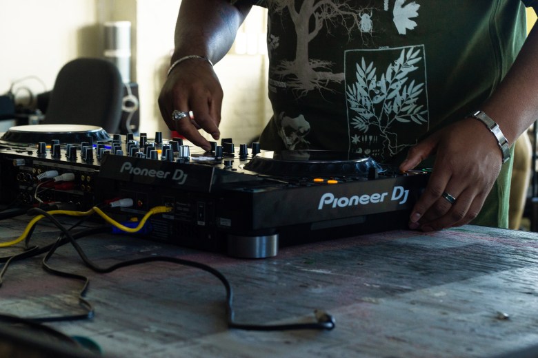 A person with brown skin playing CDJs