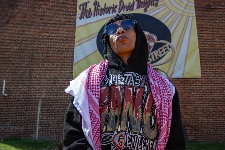 PFK Boom, a Black man, poses in front of a sign that says "the historic Druid Heights.