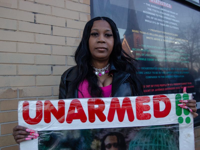 Tawanda Jones, a Black woman, holds a sign that reads: "unarmed."