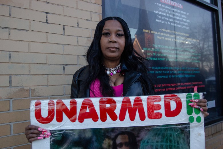Tawanda Jones, a Black woman poses while holding a sign.