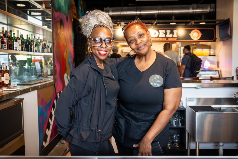 Two women pose together while smiling.