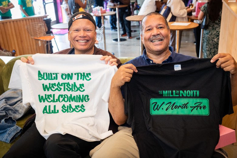 Two men hold up t-shirts