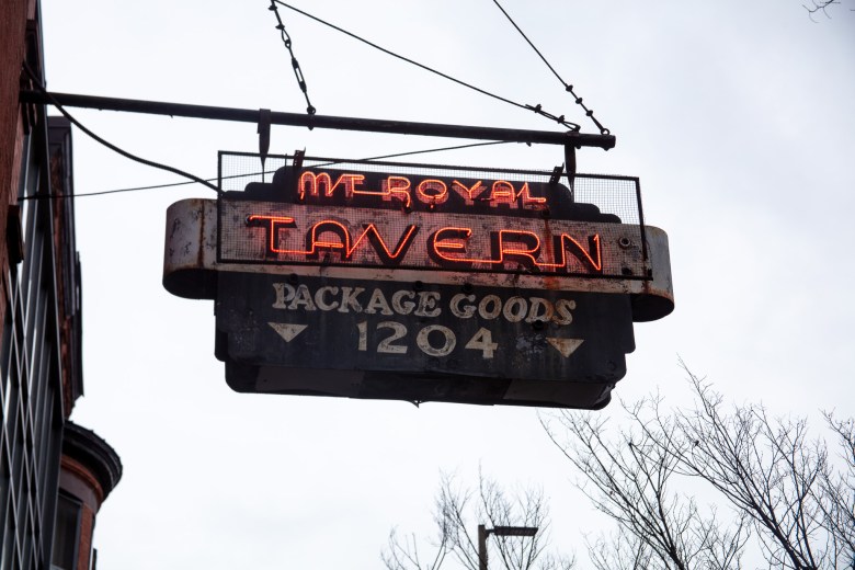 A sign suspended from a building. The sign reads: Mount Royal Tavern