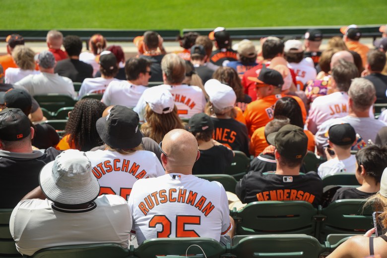 A photo taken from behind of seated Orioles fans watching the game.