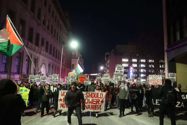 People walking down a street holding signs and banners.