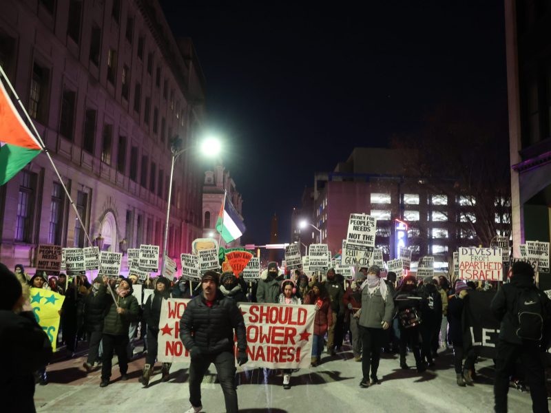 People walking down a street holding signs and banners.