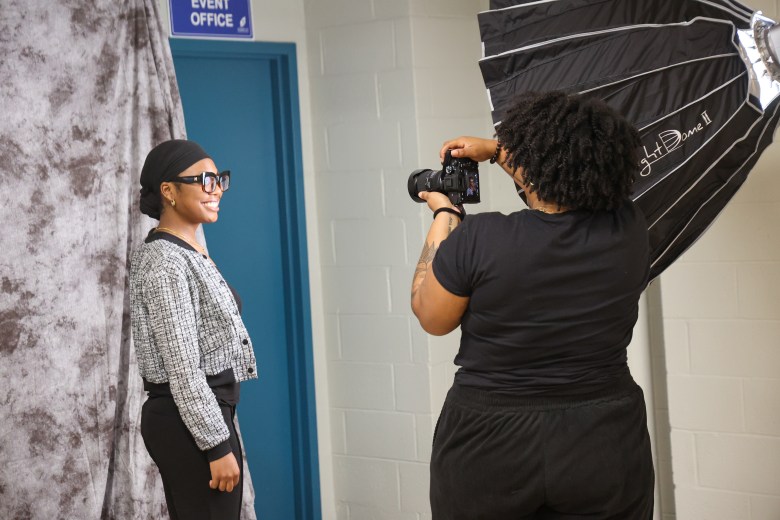 A person with brown skin is taking the portrait of an attendee at an event