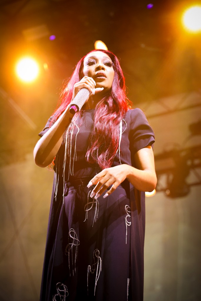 A woman holds a mic a and looks into the crowd.