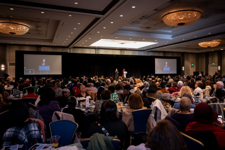 A photo of the crowd at the Booklovers' Breakfast. Tables of people watching a screen can be seen.