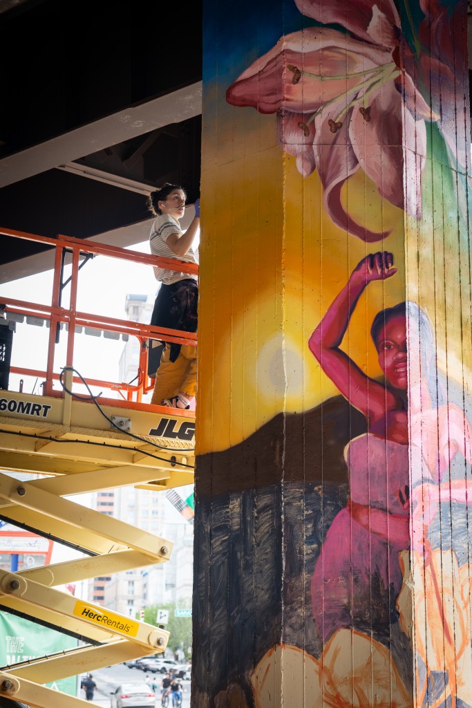 Rowan Bathurst on a lift painting on a pillar under the Jones Falls Expressway.