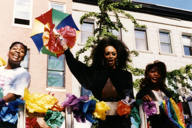 Three femmes with paper flowers at the Pride Parade in Baltimore, Maryland.