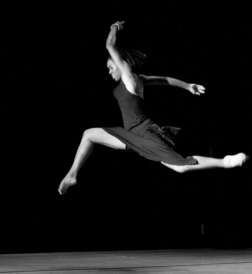 a ballerina with brown skin dances across a stage