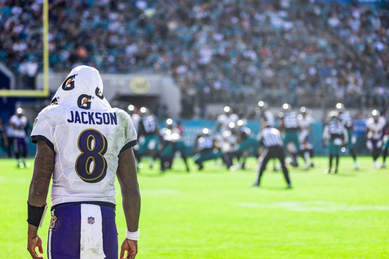 A photo of the back of football player Lamar Jackson and he stands on the field.