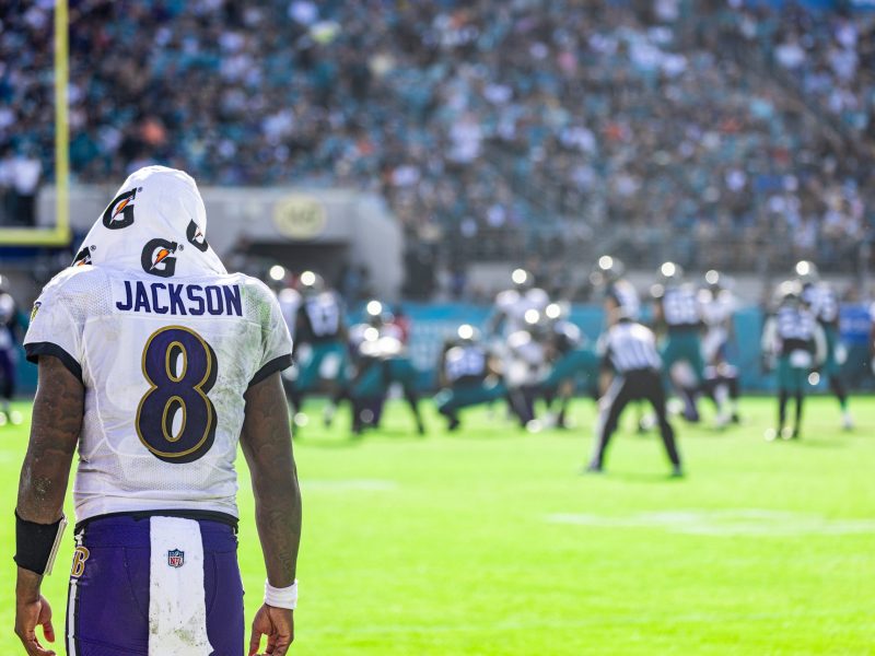 A photo of the back of football player Lamar Jackson and he stands on the field.