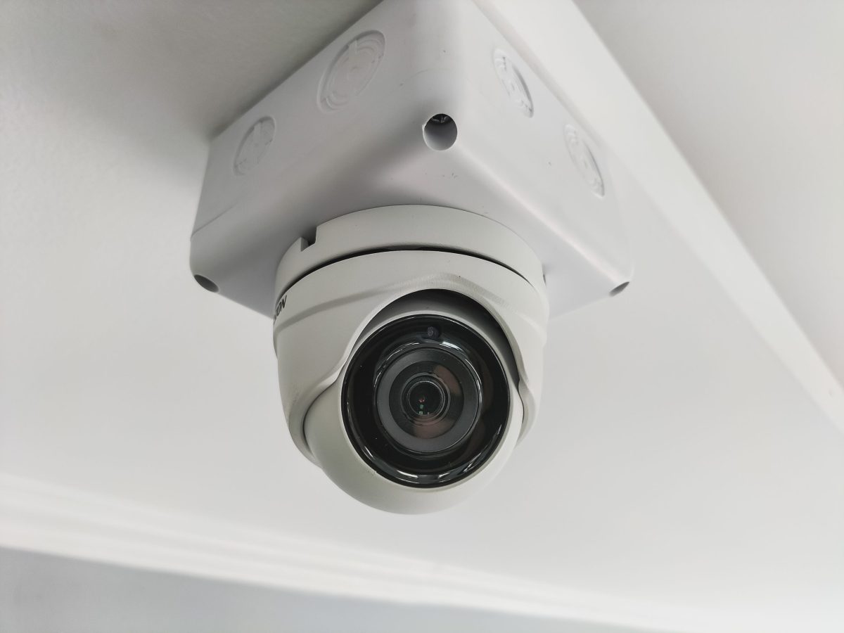 A white CCTV camera on the ceiling inside the building.