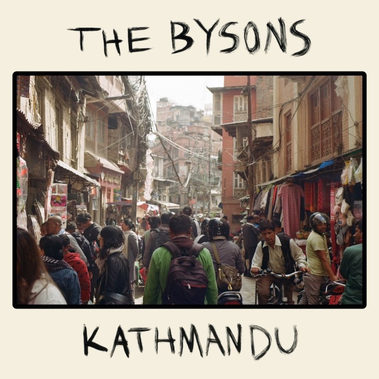 An image of album cover art. Text reads: "The Bysons" and "Kathmandu." A picture of a crowded and busy street is between the text.