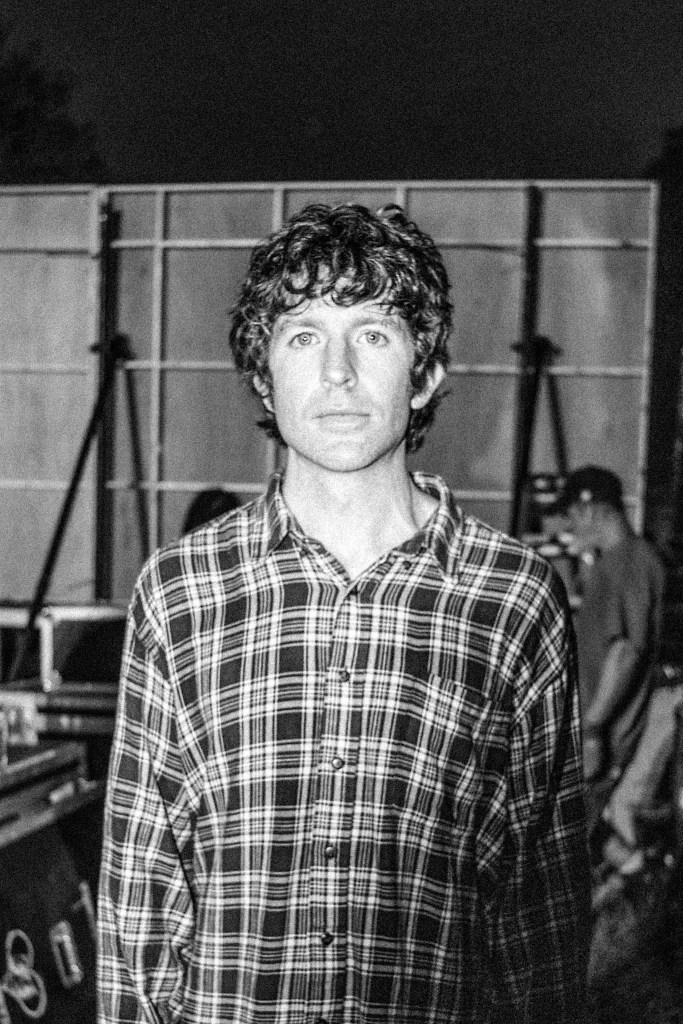A photo of Brendan Yates. He wears a plaid button-down shirt and looks into the camera.