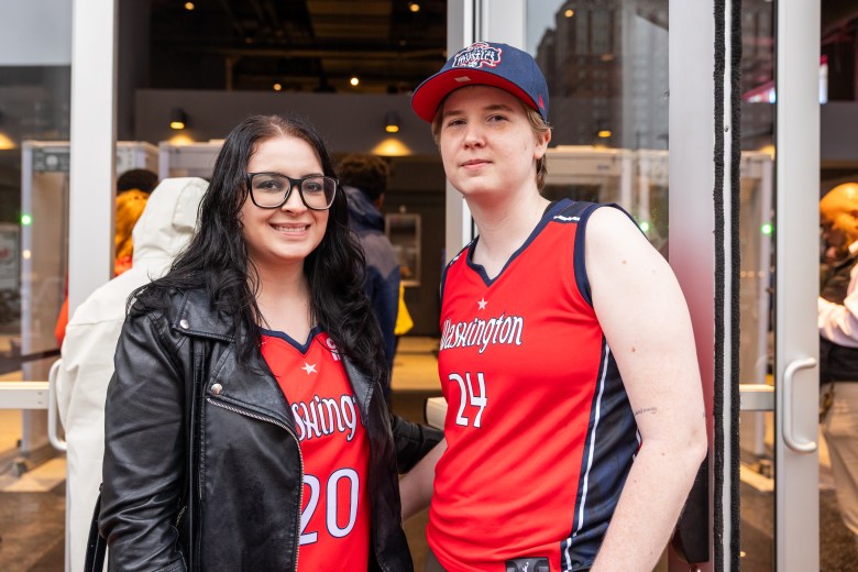 Two people wearing Washington Mystics jerseys pose for the camera.