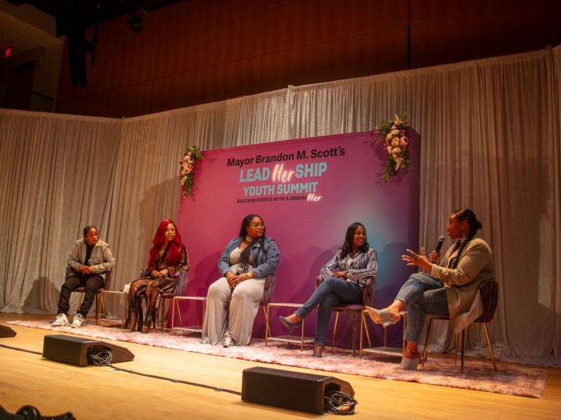 Five women sit on a panel at Mayor Brandon M. Scott’s Youth Summit 2024: InfluenceHER.