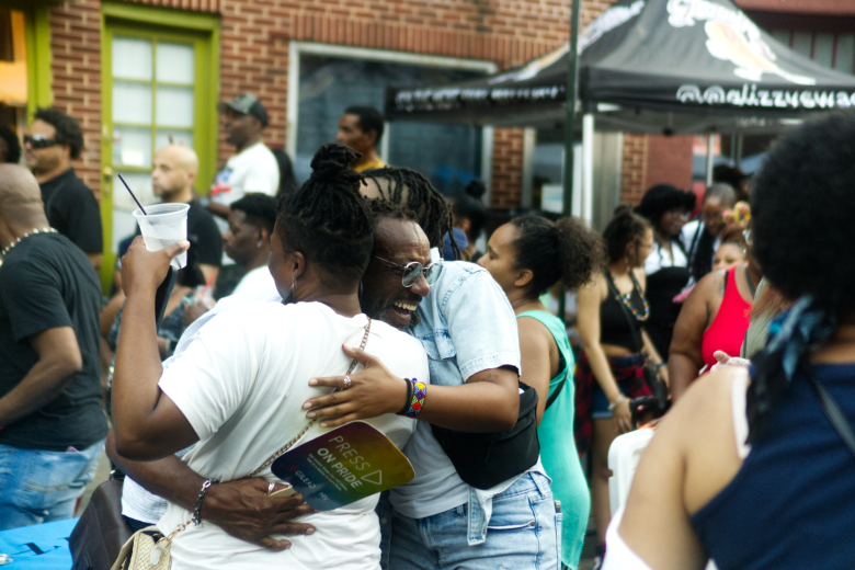Three people hug while standing in a crowd.